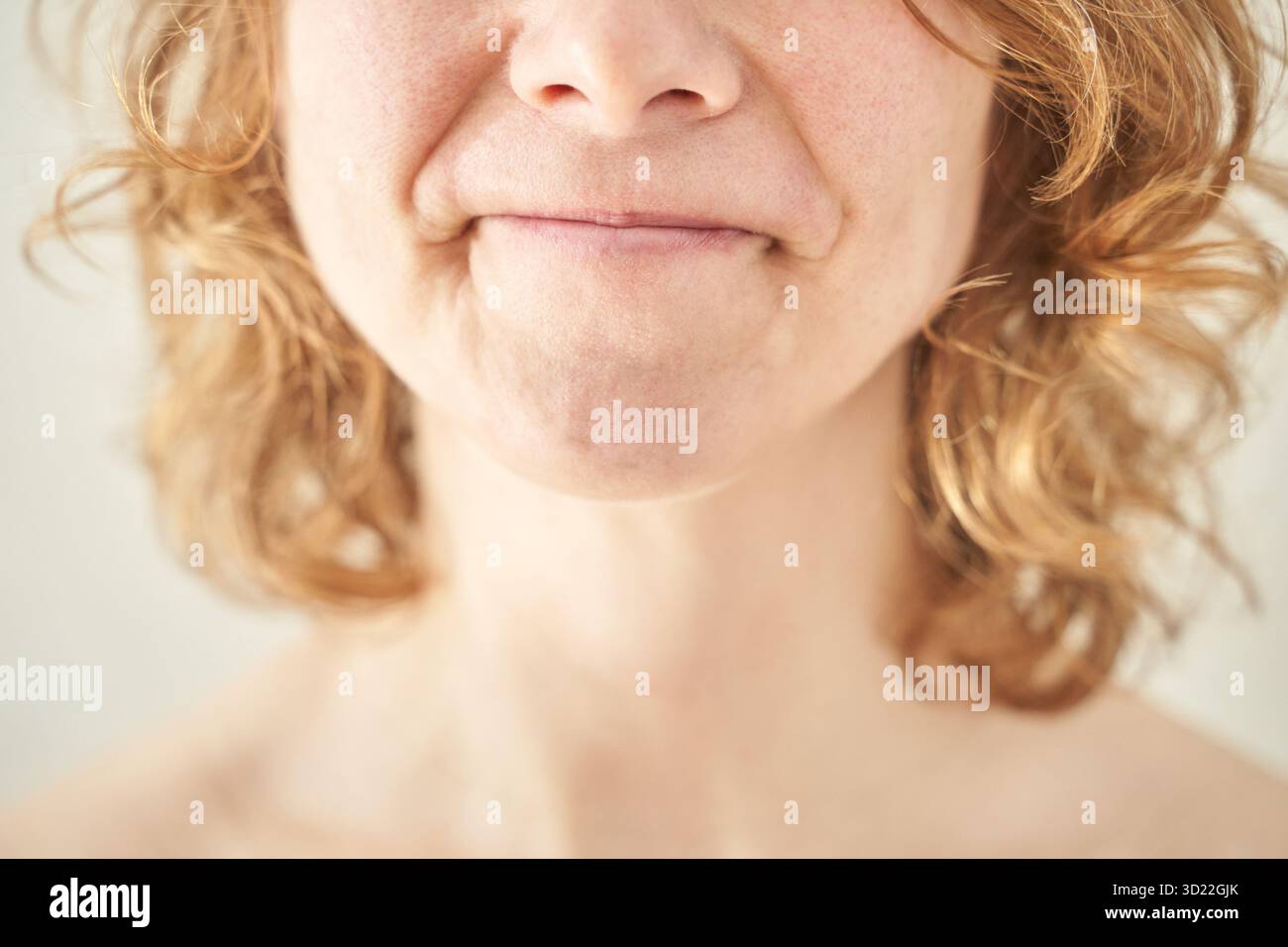 Primo piano di una donna caucasica con capelli ricci e un sorriso sottile Foto Stock