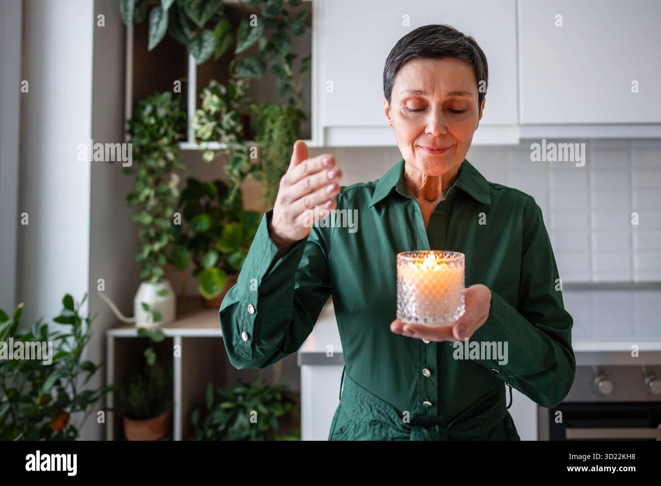 Donna tranquilla che inala il profumo di candela, trattamento aromaterapico riposo. Consapevolezza, cura di sé a casa Foto Stock