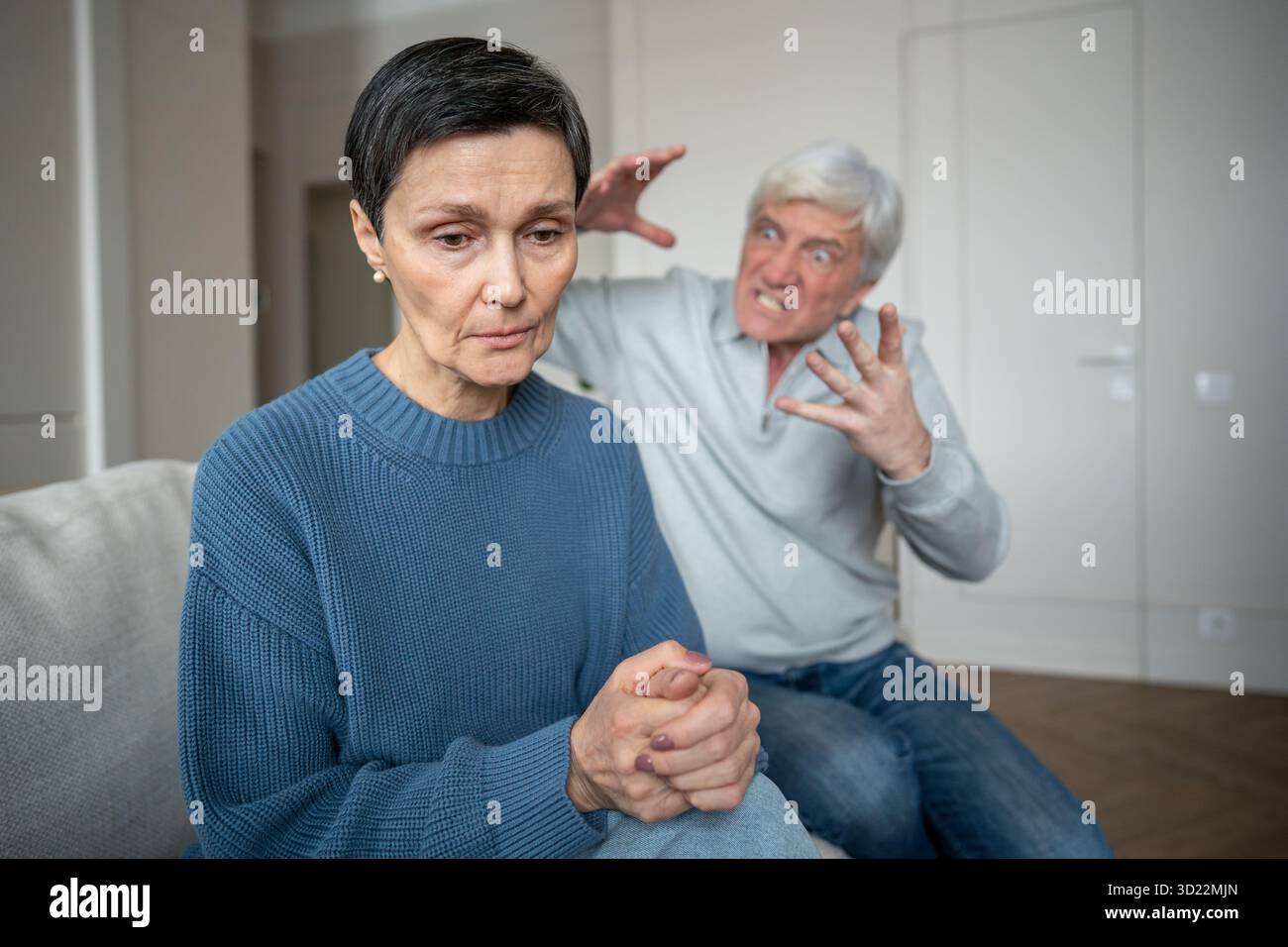 Donna distaccata concentrata verso l'interno temendo gridi del marito e gesti in background, stress emotivo Foto Stock