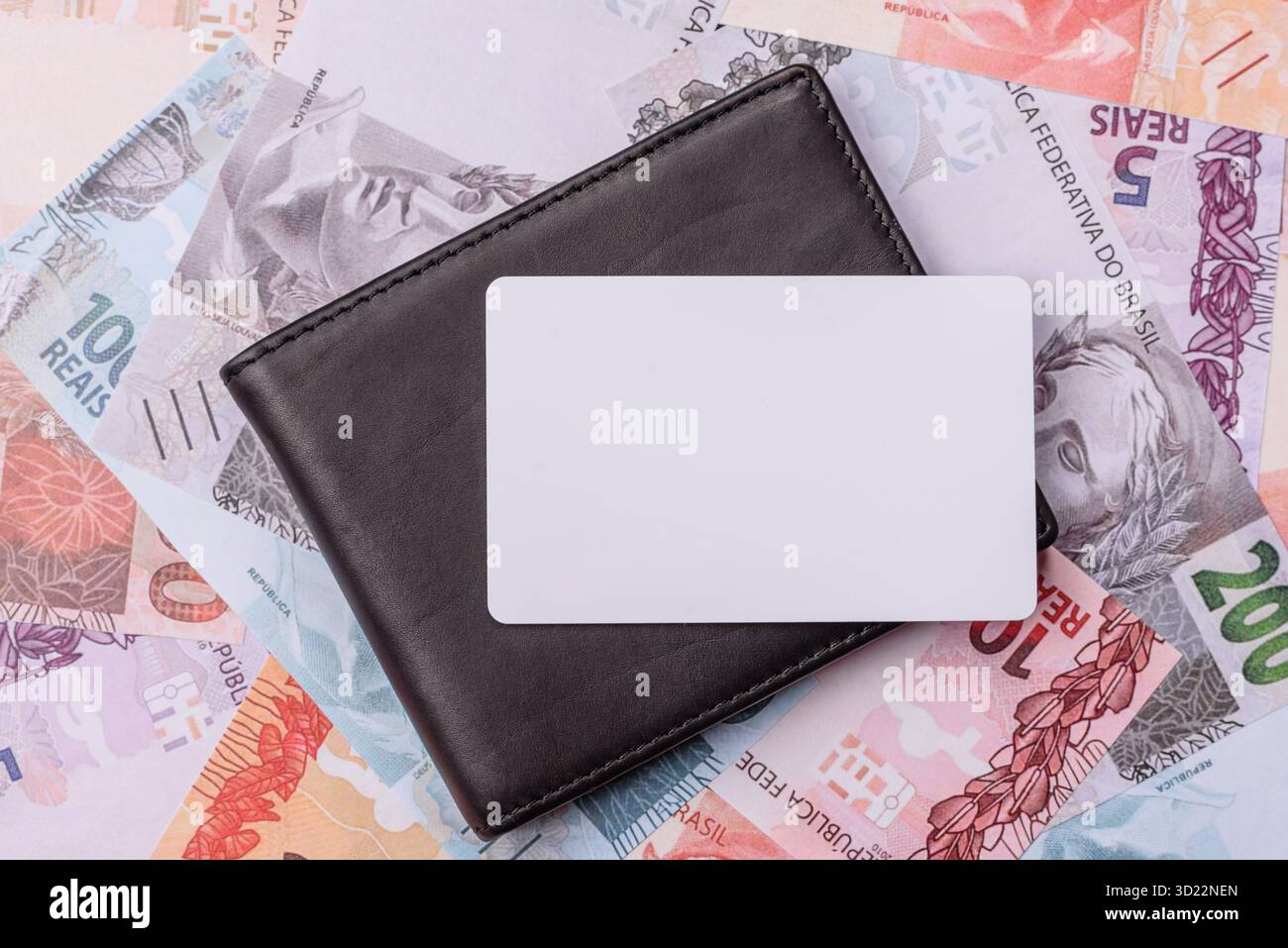 La carta di plastica bianca come simbolo dei pagamenti senza contanti sullo sfondo di denaro cartaceo del Brasile Foto Stock