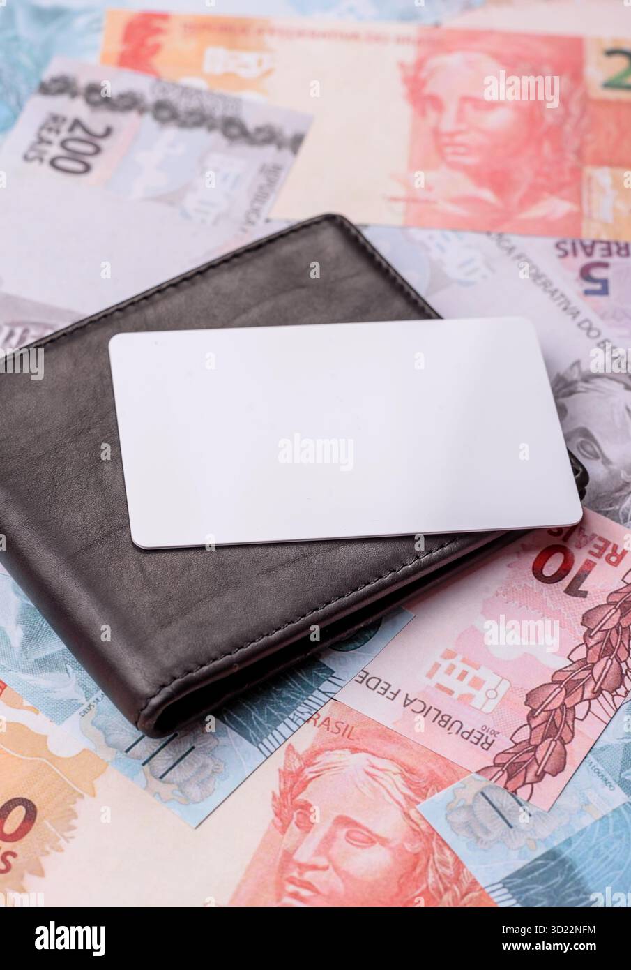 La carta di plastica bianca come simbolo dei pagamenti senza contanti sullo sfondo di denaro cartaceo del Brasile Foto Stock