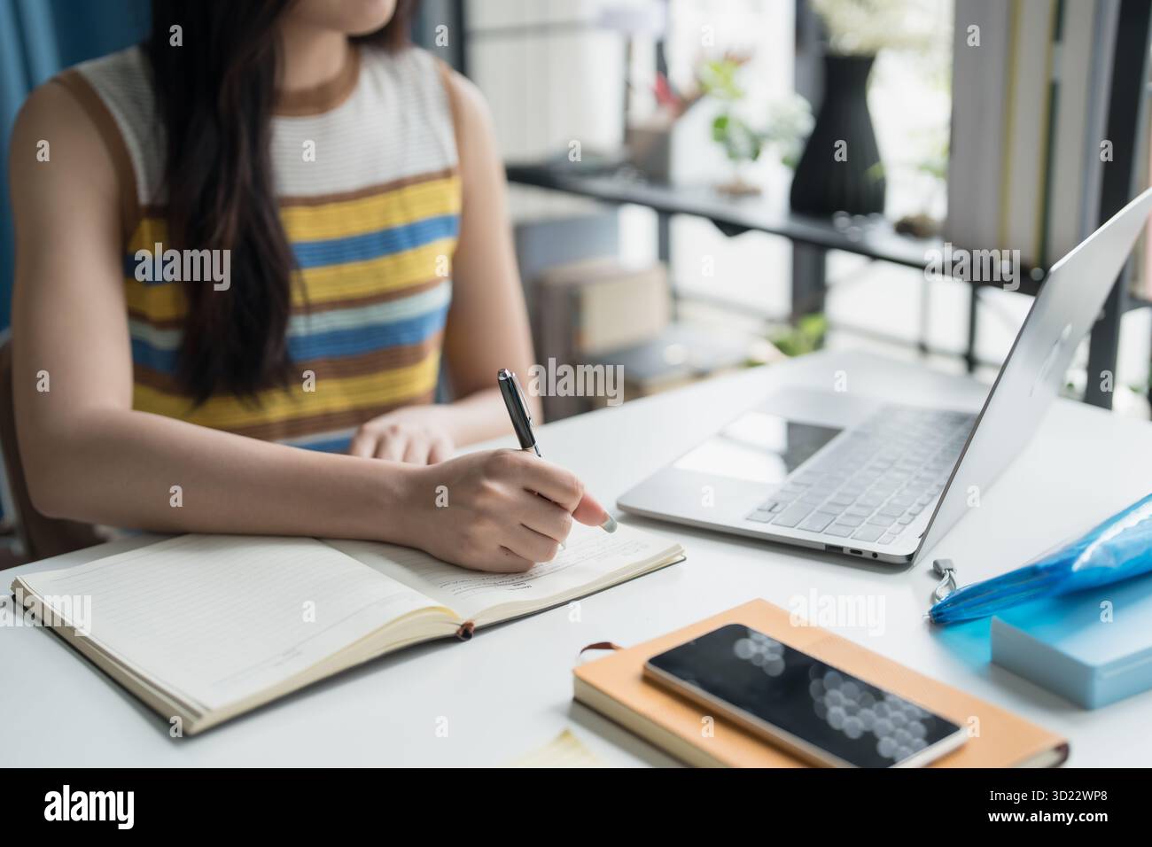 Studentessa donna asiatica focalizzata sull'apprendimento online con notebook a casa. Foto Stock