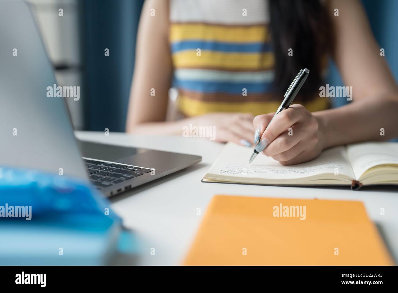 Studentessa donna asiatica focalizzata sull'apprendimento online con notebook a casa. Foto Stock