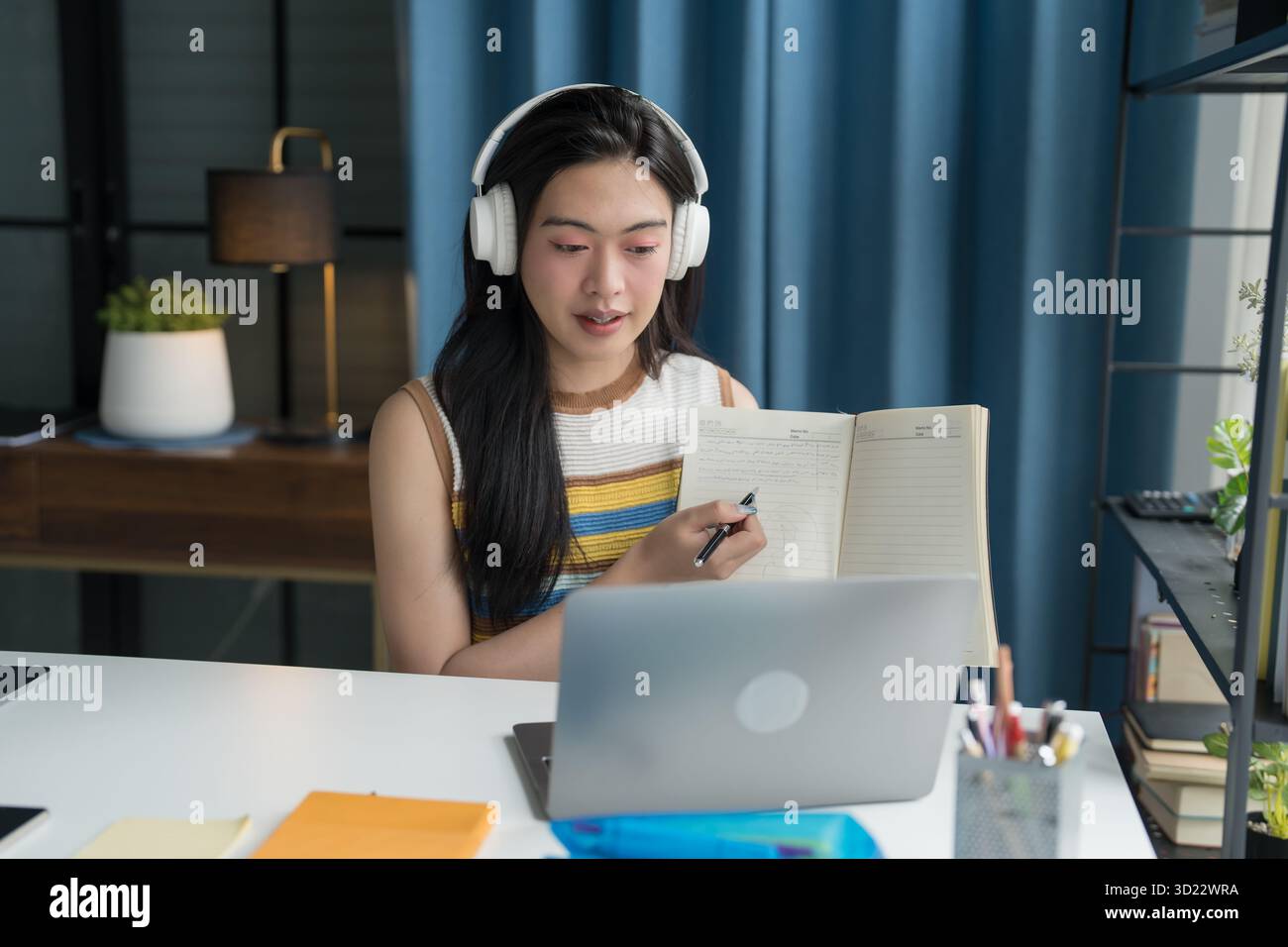 Giovane tutor asiatico con cuffia e sorridente videochiamata che spiega la lezione di Tutoring online da casa. Foto Stock