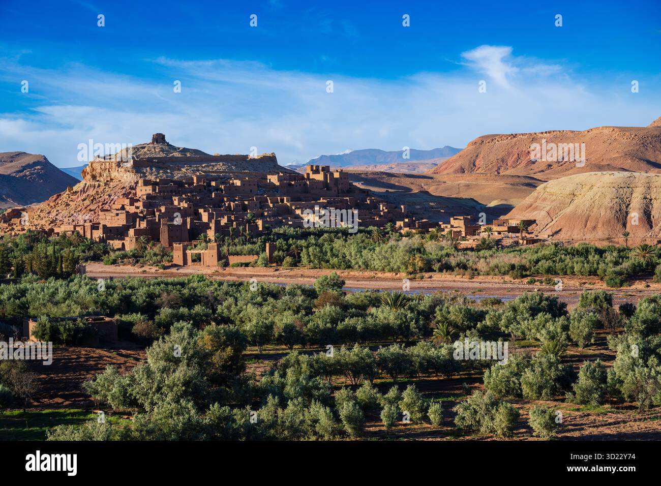 Antico villaggio con edifici in argilla circondato da vegetazione lussureggiante in un paesaggio desertico. Ait Benhaddou. Marocco Foto Stock