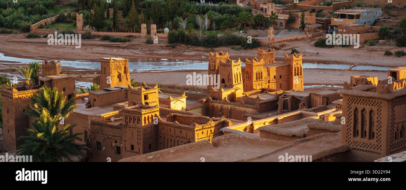 Antico villaggio desertico con architettura in mattoni di fango e palme, inondato di luce calda. Ait Benhaddou. Marocco Foto Stock