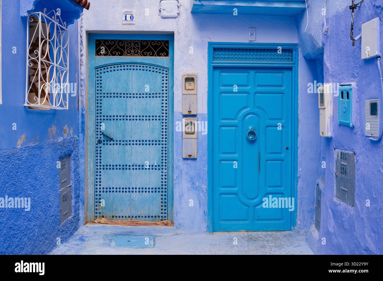 Porte e pareti blu vibranti in uno stretto vicolo con ornati lavori in metallo. Chefchaouen, Marocco Foto Stock