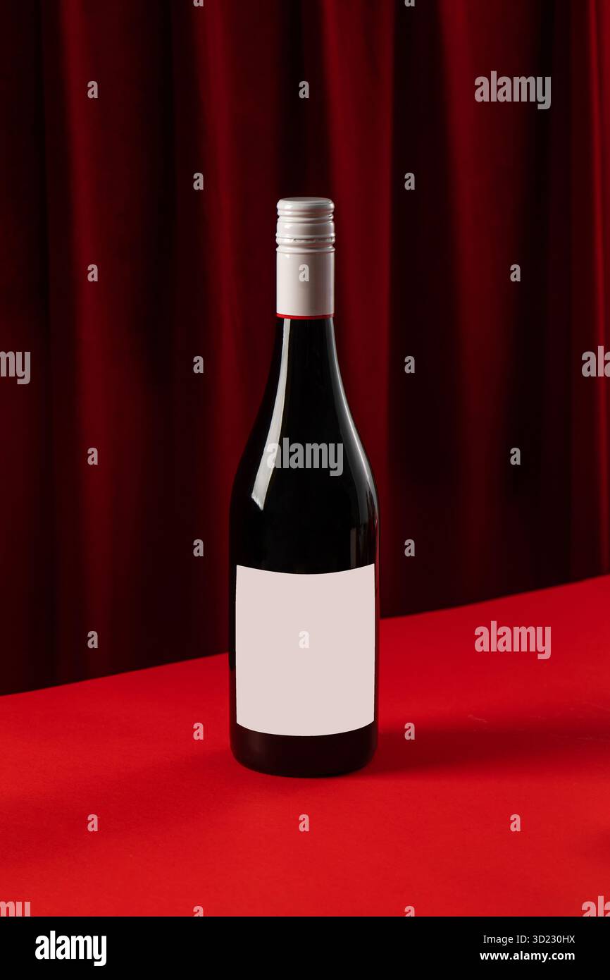 Elegante bottiglia di vino rosso con etichetta vuota su sfondo rosso Foto Stock