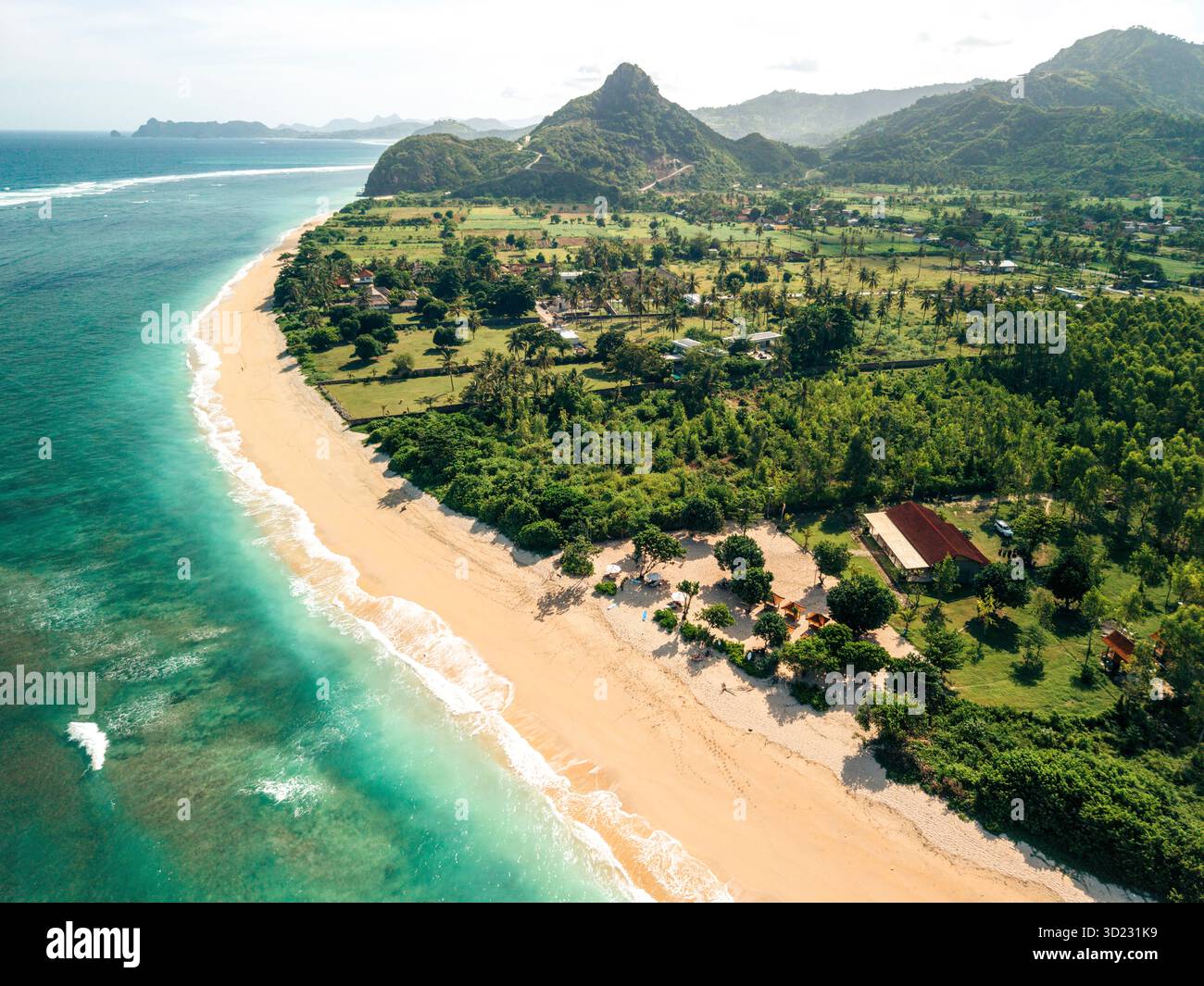Vista aerea panoramica di una spiaggia tropicale con vegetazione lussureggiante e montagne lontane. Lombok, resto nove, Indonesia Foto Stock