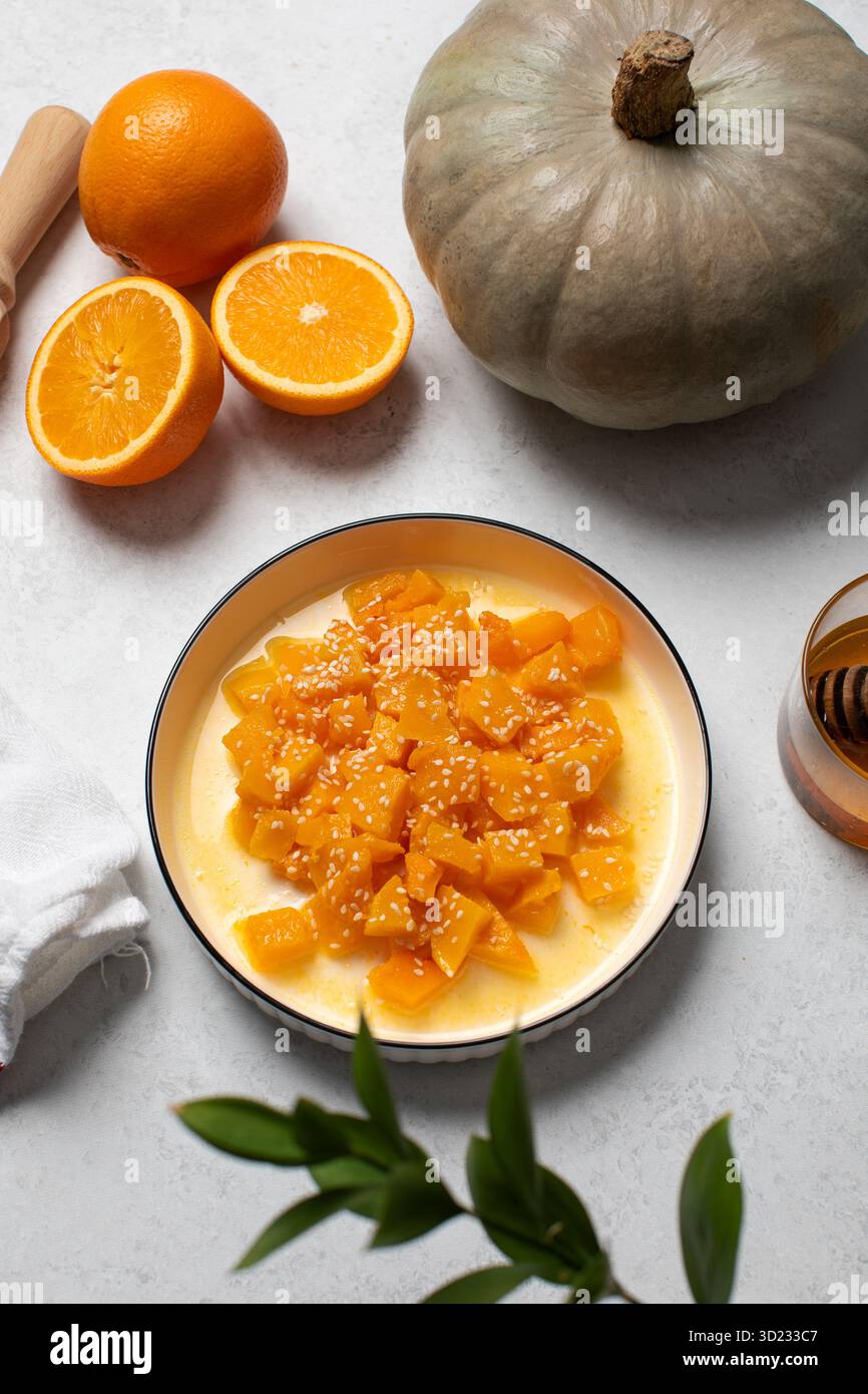 Dessert all'arancia e alla zucca con arance a fette e miele su sfondo bianco Foto Stock