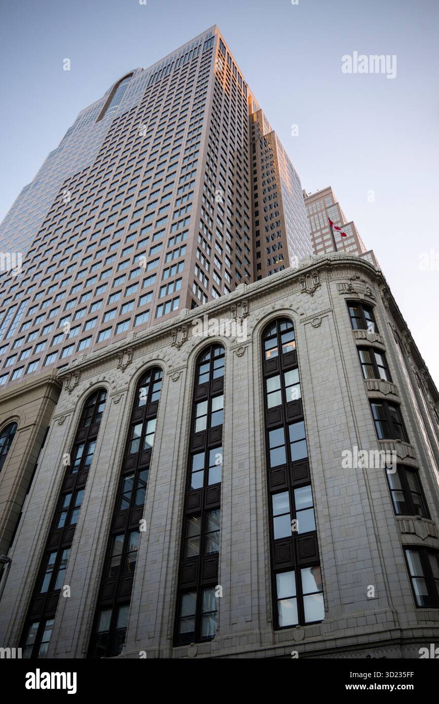 Alto e moderno grattacielo e classico edificio in pietra sotto un cielo limpido, girato dal basso. Calgary, Alberta, Canada Foto Stock