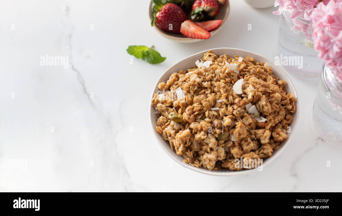 Granola croccante fatta in casa con mandorle affettate in un recipiente con fragole. Mangiare sano. Copia spazio Foto Stock