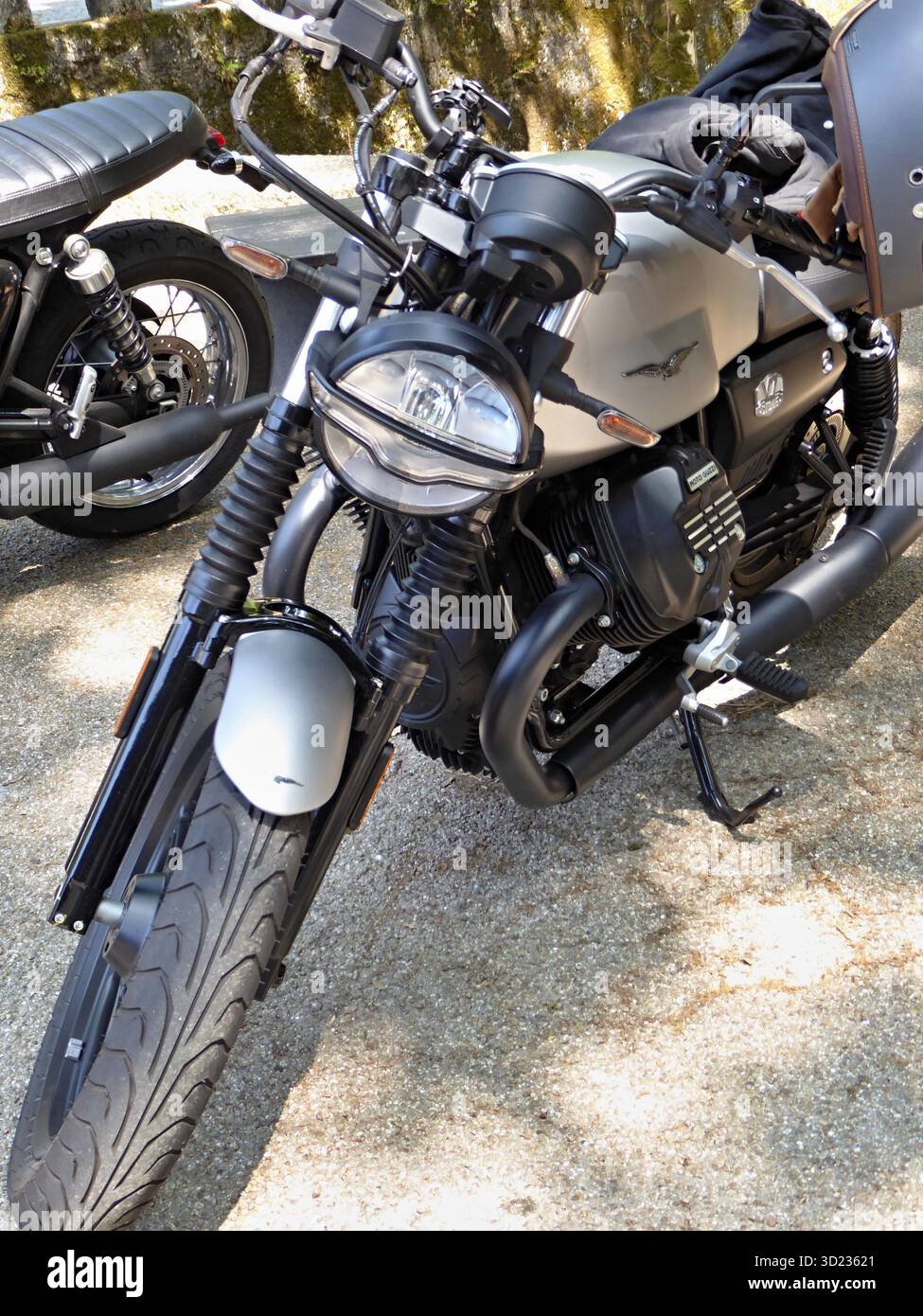 Vista frontale di una motocicletta argentata Moto Guzzi V7 Stone parcheggiata su una strada ghiaiosa, che ne mostra il design e le caratteristiche Foto Stock