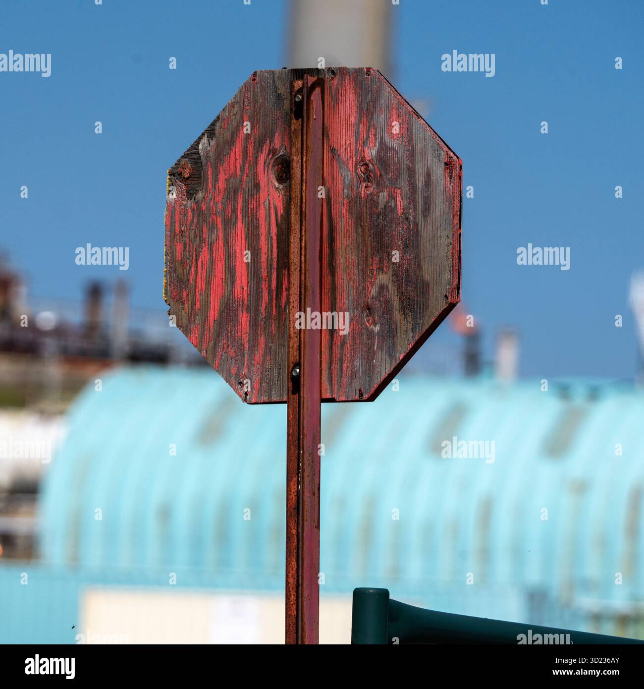 Segnale di stop in legno resistente agli agenti atmosferici sullo sfondo industriale con il cielo azzurro chiaro Pincher Creek, Alberta, Canada Foto Stock