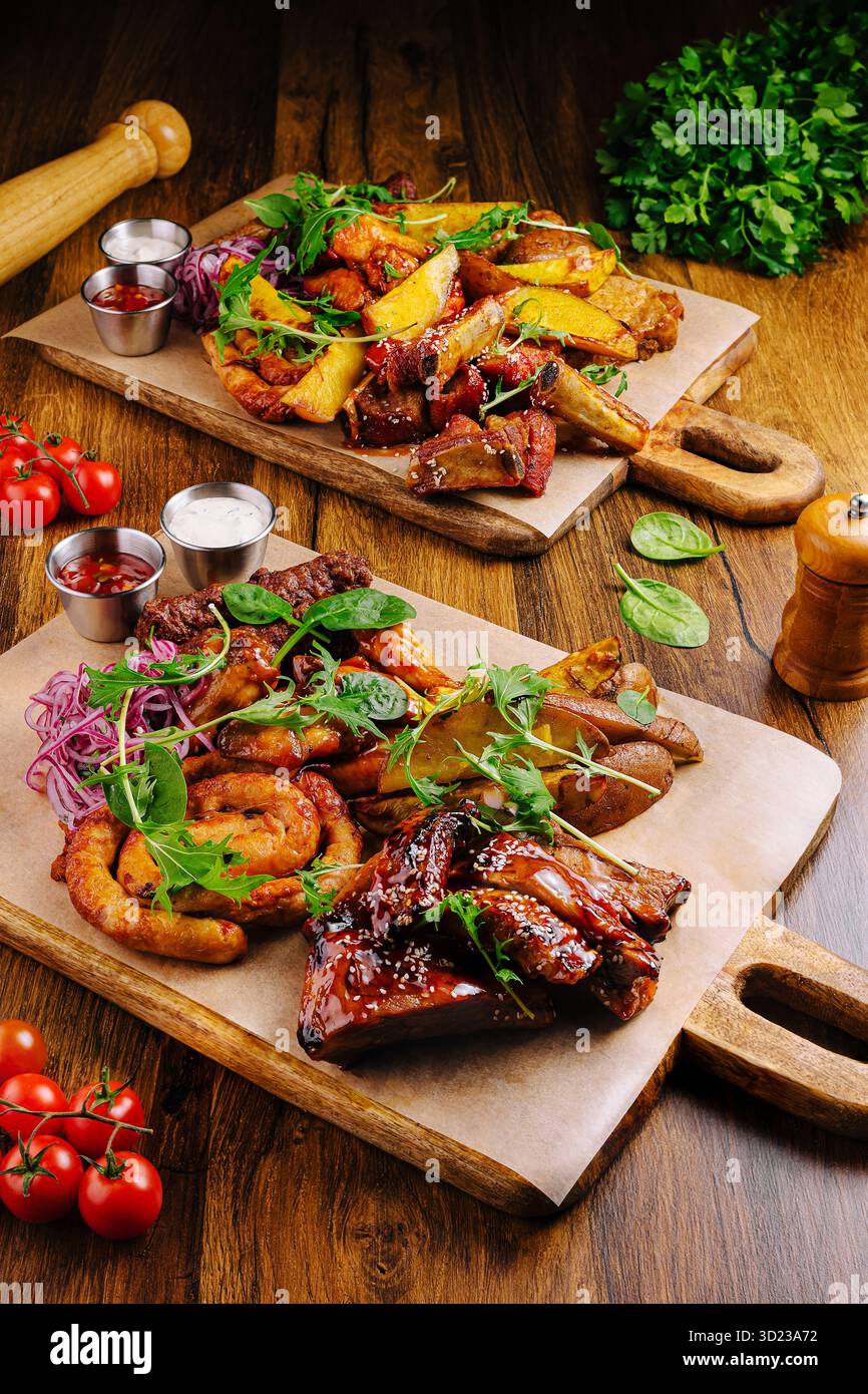 Carni alla griglia con contorni serviti su tavole di legno in un accogliente ristorante Foto Stock