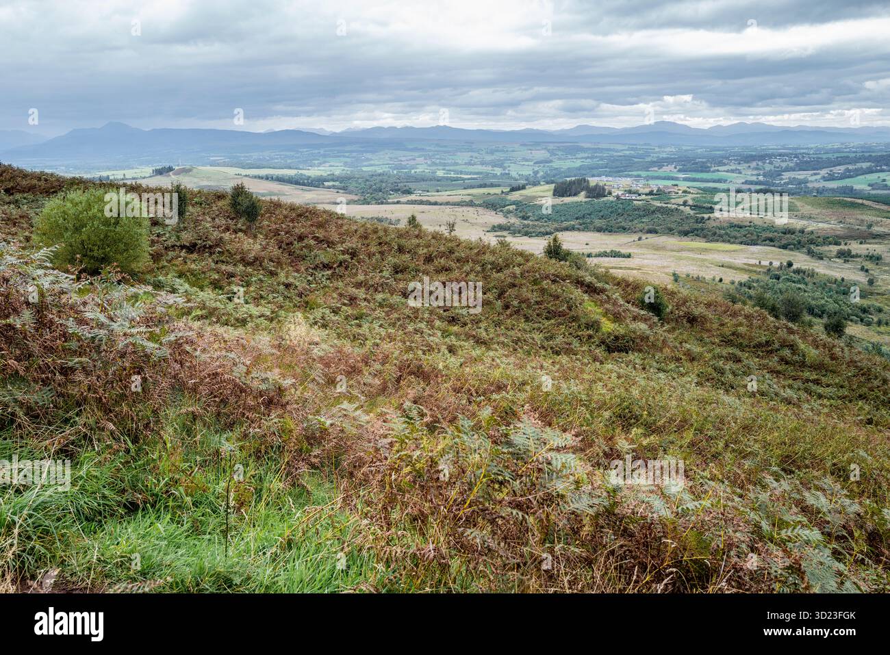 Colline e campi ondulati sotto un cielo nuvoloso con vedute lontane delle montagne. Foto Stock