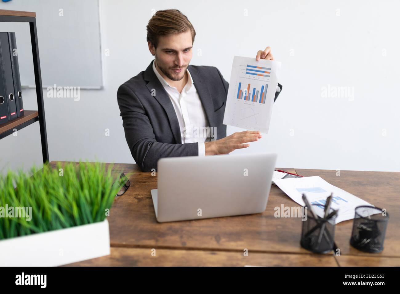 Manager in una tuta aziendale dimostra un programma mentre comunica tramite collegamento video utilizzando un notebook Foto Stock