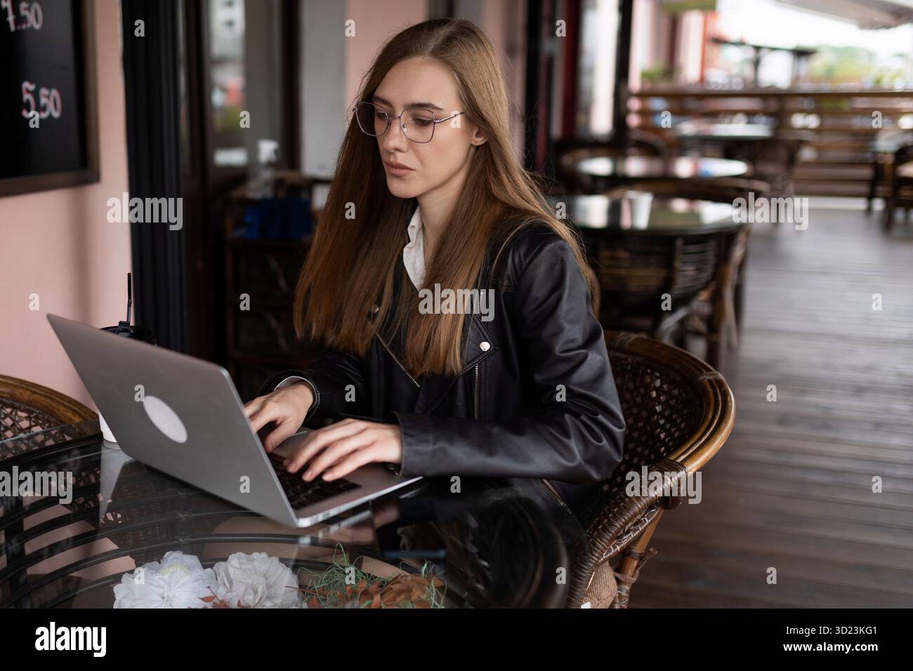Giovane donna che lavora su un notebook in un bar della città Foto Stock
