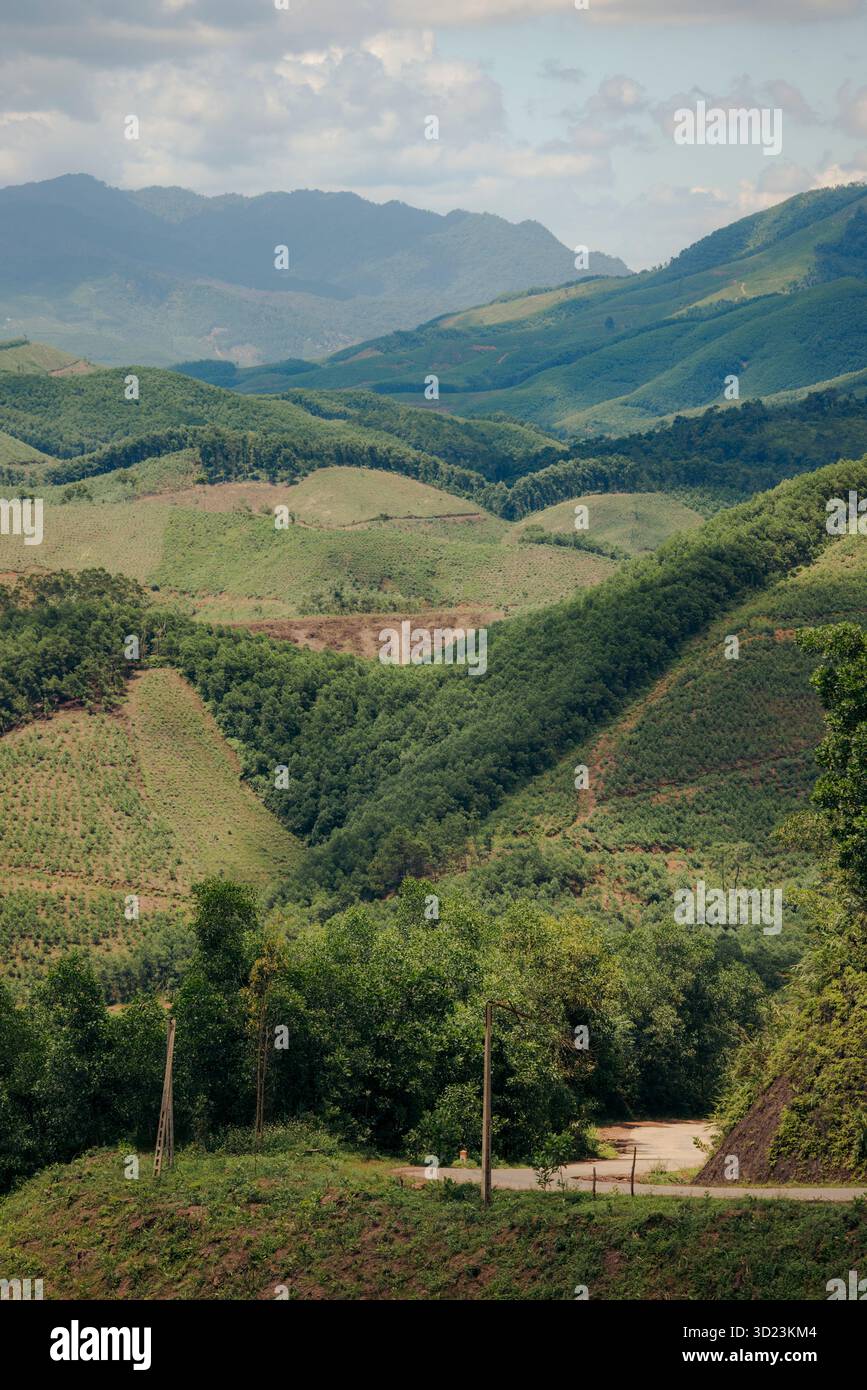 Colline verdi ondulate e valli sotto un cielo nuvoloso con vedute lontane delle montagne. Distretto di Son Dong, Bac Giang, Vietnam Foto Stock