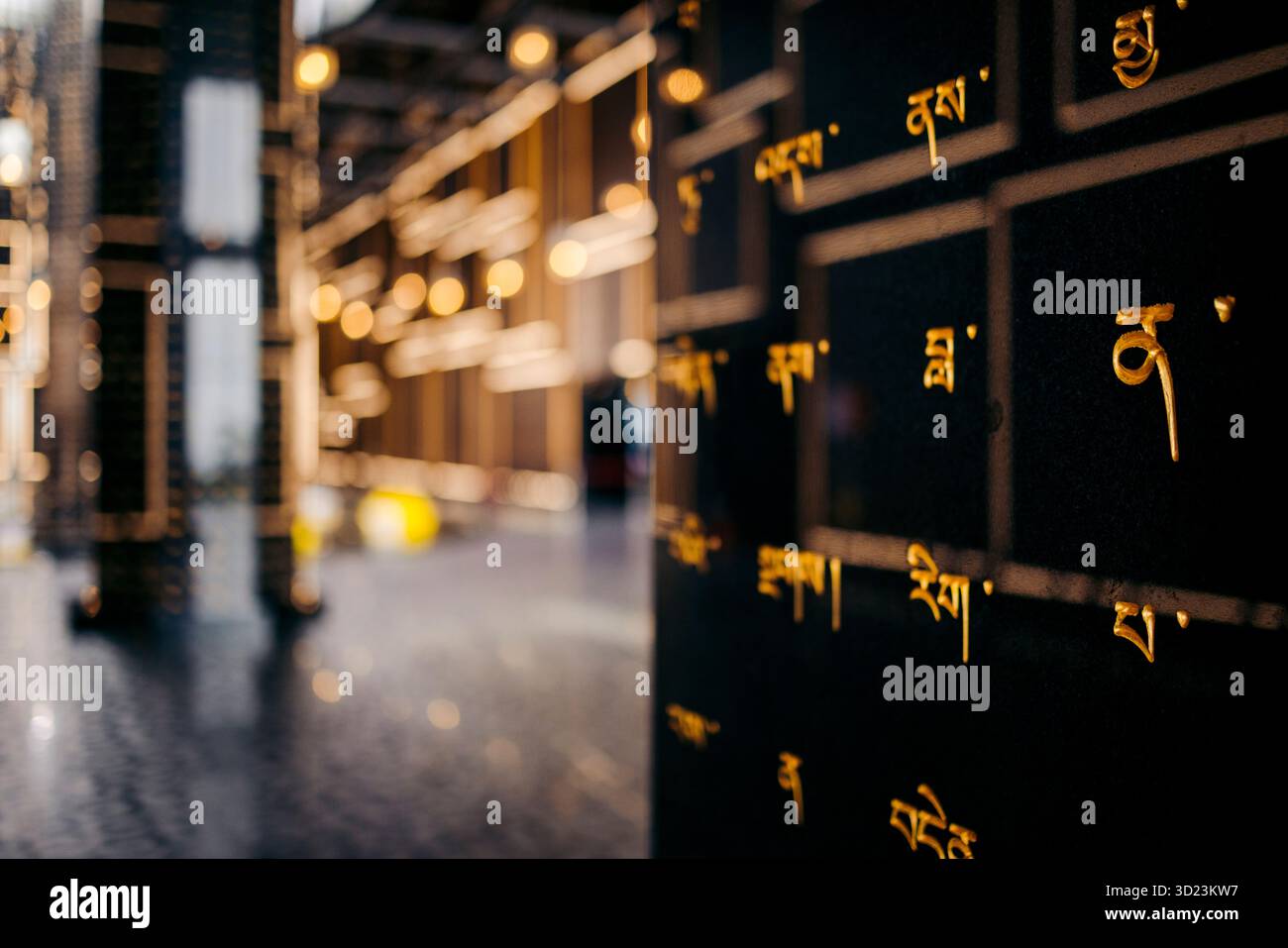 Scritta dorata su pietra scura con luci soffuse in uno spazio architettonico moderno. Black Virgin Mountain, Tay Ninh, Vietnam Foto Stock