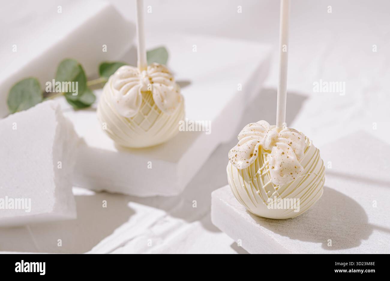 Il dessert decorativo si apre su uno sfondo bianco pulito con accenti di verde Foto Stock