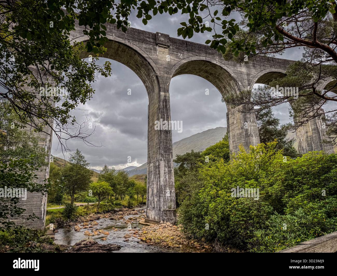 Maestosi archi di viadotti in pietra sopra la lussureggiante valle verde con un tranquillo fiume sottostante. Glenfinnan Viaduct, Scozia Foto Stock