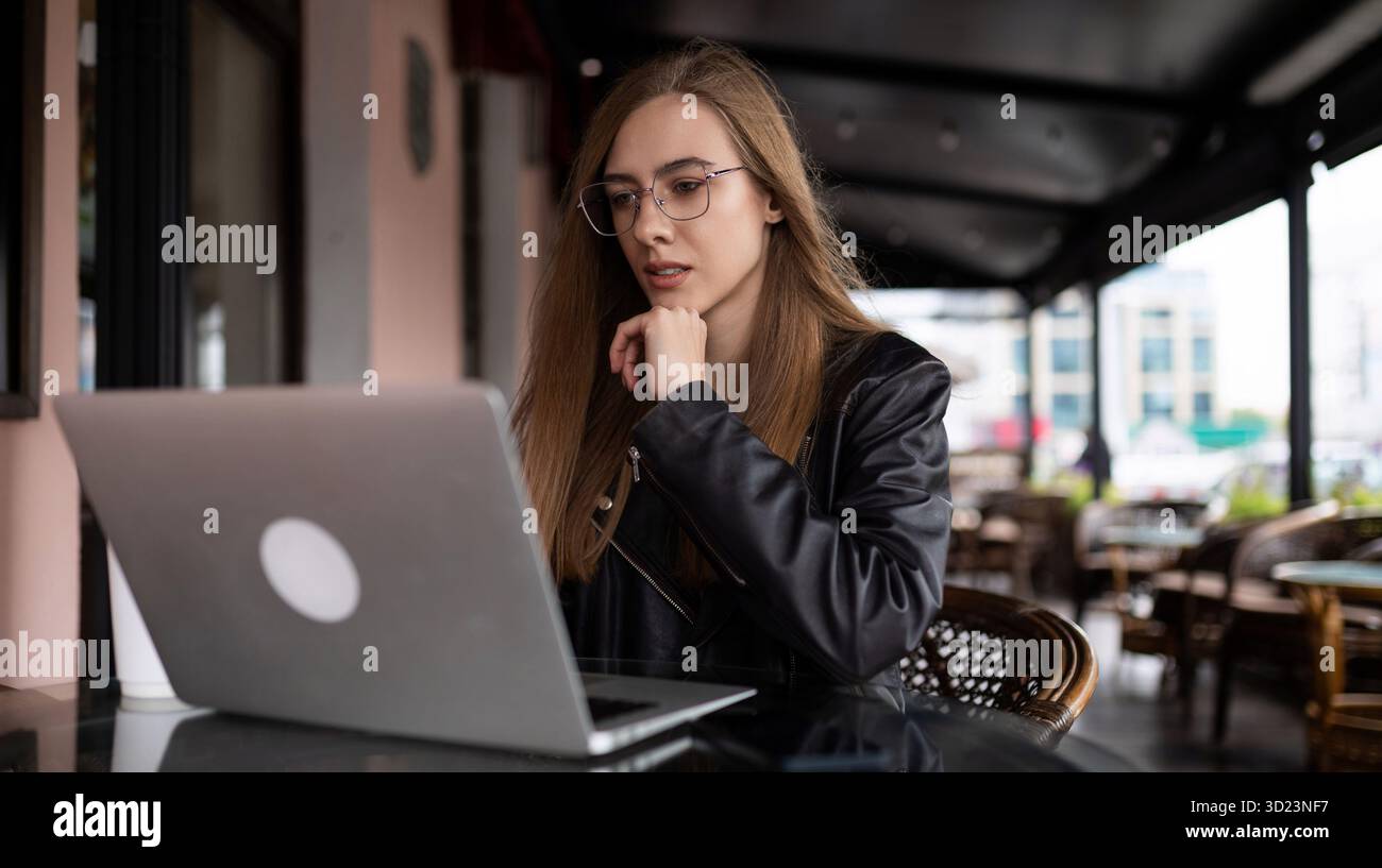 Giovane donna che lavora online con un laptop in un caffè della città Foto Stock