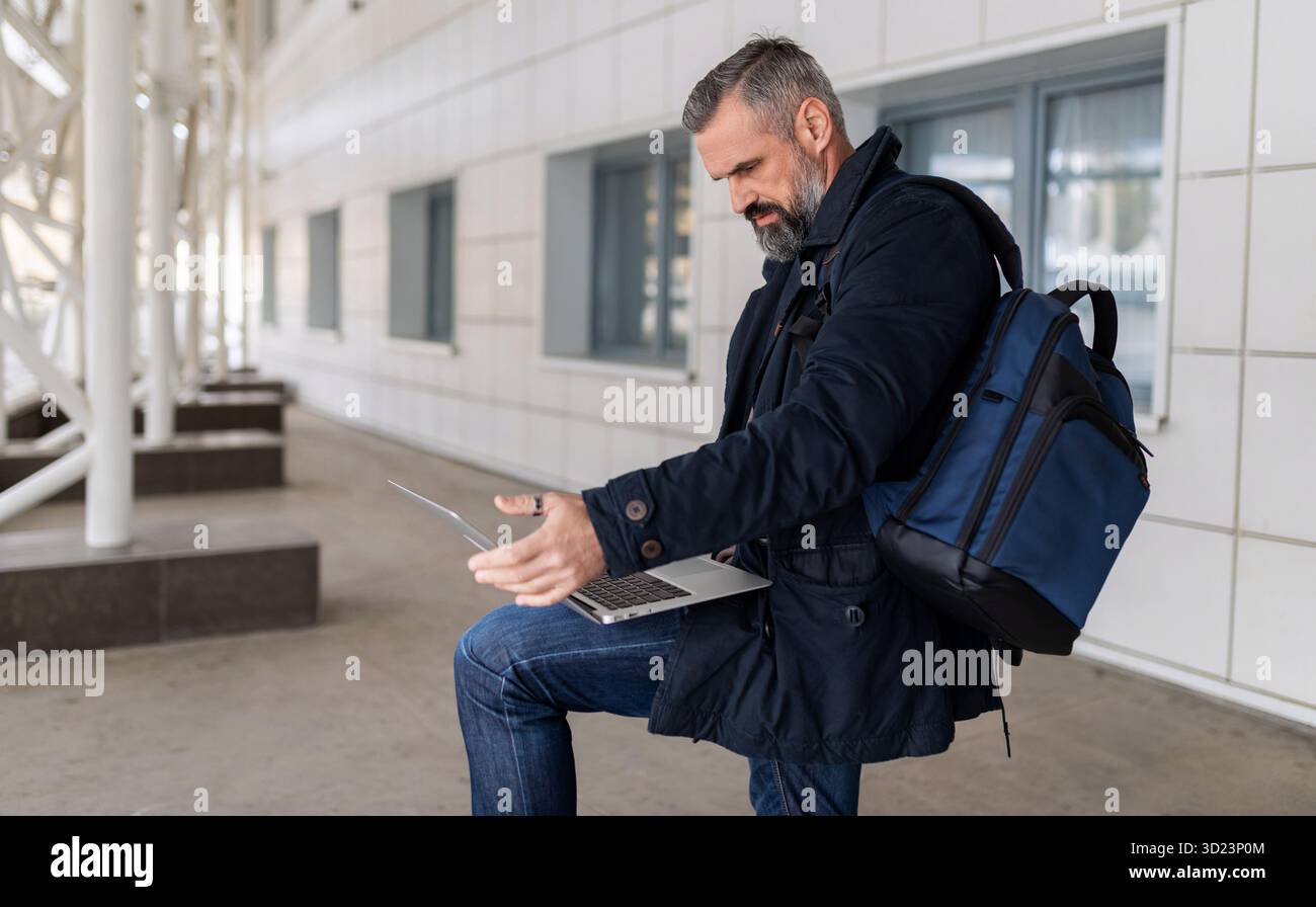 Imprenditore uomo maturo che lavora su un laptop online nella lounge dell'aeroporto, concetto di lavoro freelance Foto Stock