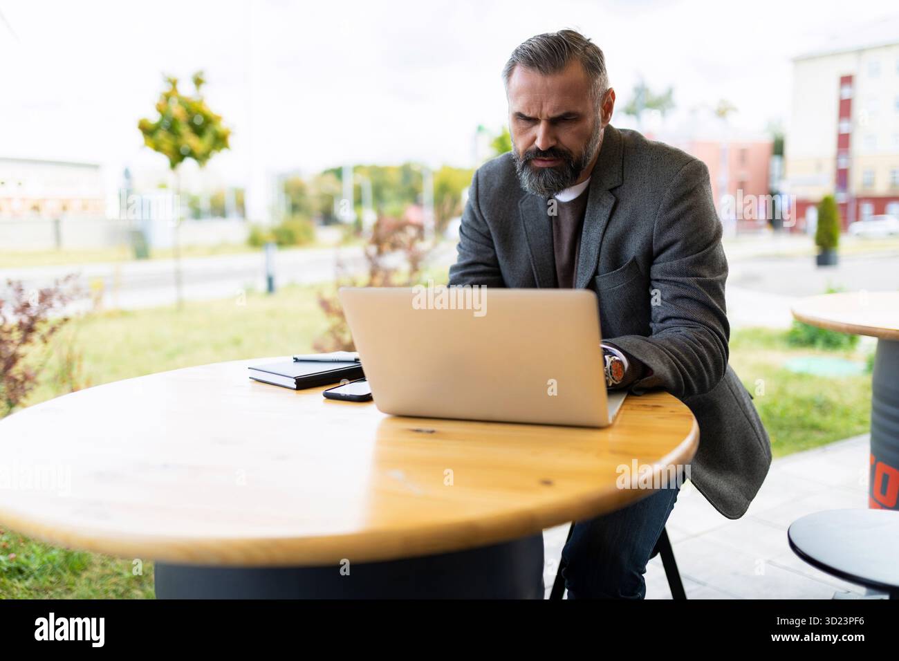 Imprenditore uomo maturo che lavora online in un bar su un computer portatile Foto Stock