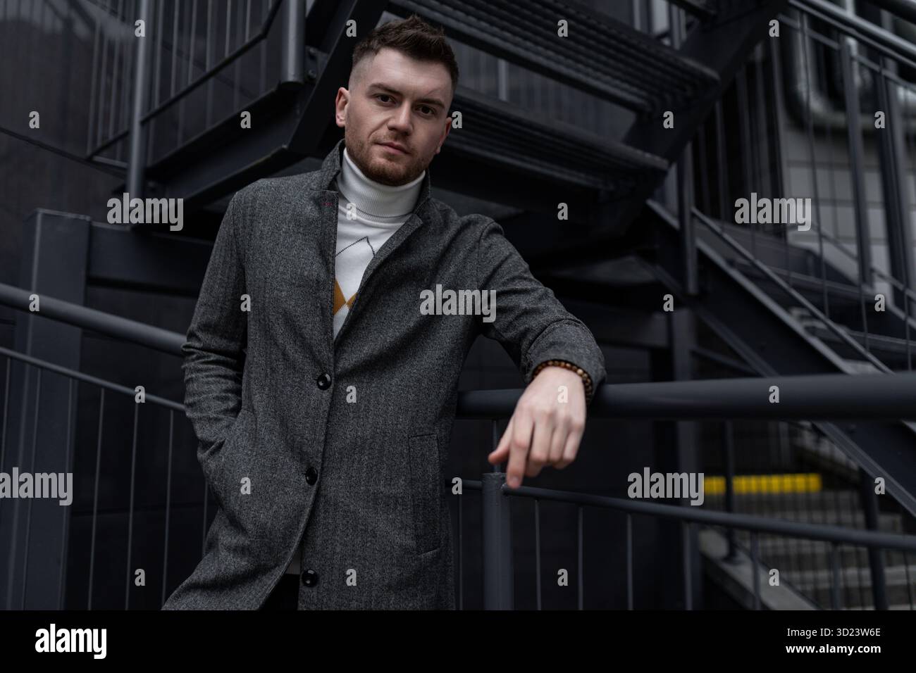 Elegante giovane caucasico, uomo con cappotto autunnale su scale nere all'esterno Foto Stock