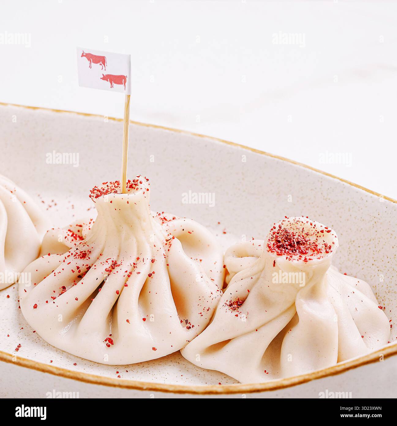 Gnocchi o khinkali serviti in una ciotola con bandiere decorative e spezie su un tavolo Foto Stock