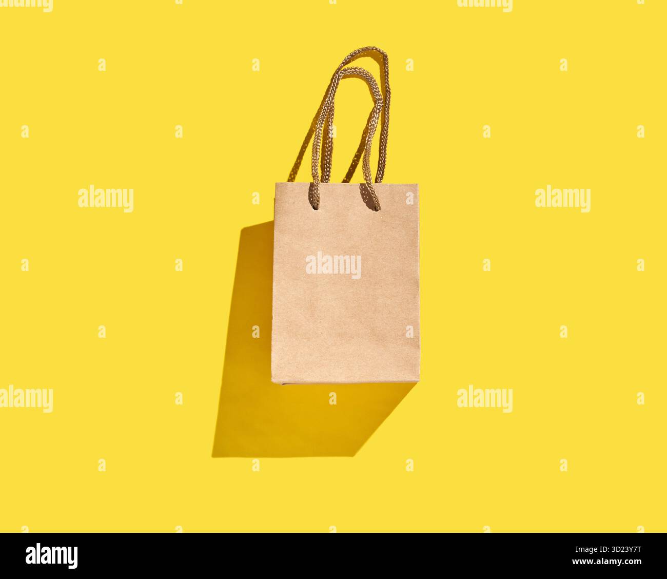 Borsa per la spesa in carta marrone con manici su sfondo giallo brillante Foto Stock