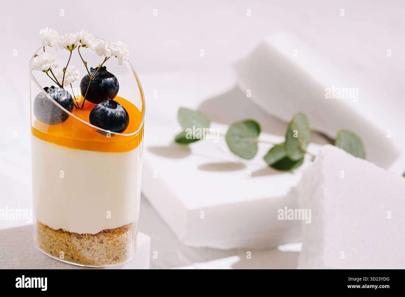 Delizioso dessert con condimento all'arancia e frutti di bosco freschi su sfondo bianco Foto Stock