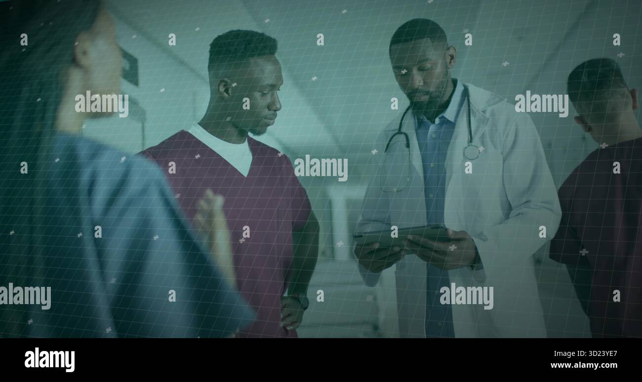 Membri del team medico che esaminano tablet in corridoio dell'ospedale, con stetoscopio scrub blu Bordeaux Foto Stock