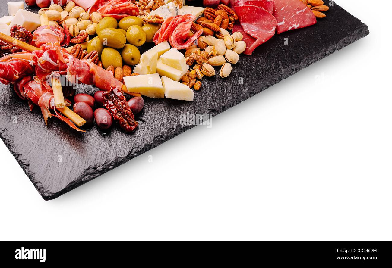 Tagliere di salumi e formaggi assortiti su un tagliere di ardesia con noci e olive Foto Stock