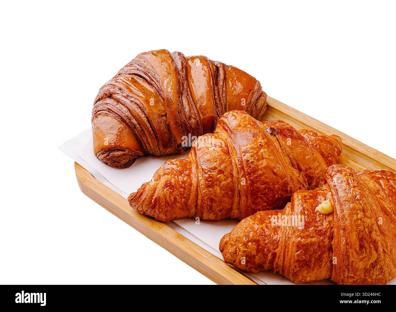Croissant appena sfornati disposti su un vassoio di legno con un caldo bagliore Foto Stock