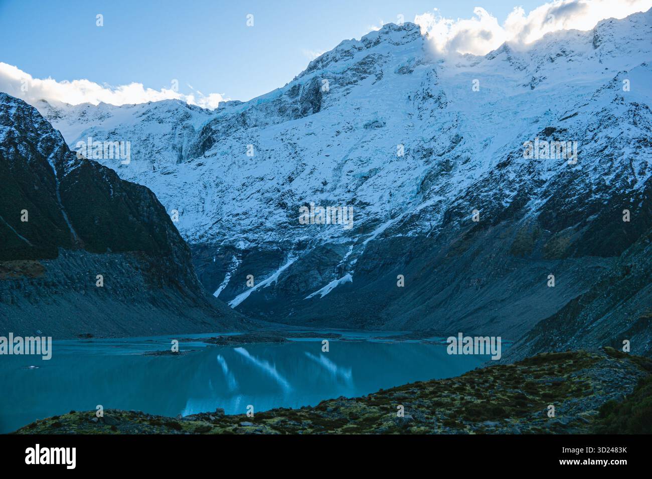 Le imponenti vette innevate si riflettono nelle acque cristalline di un lago glaciale. Foto Stock