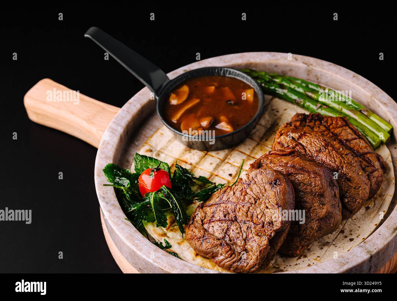 Bistecca alla griglia servita su un piatto frizzante con verdure e salsa Foto Stock