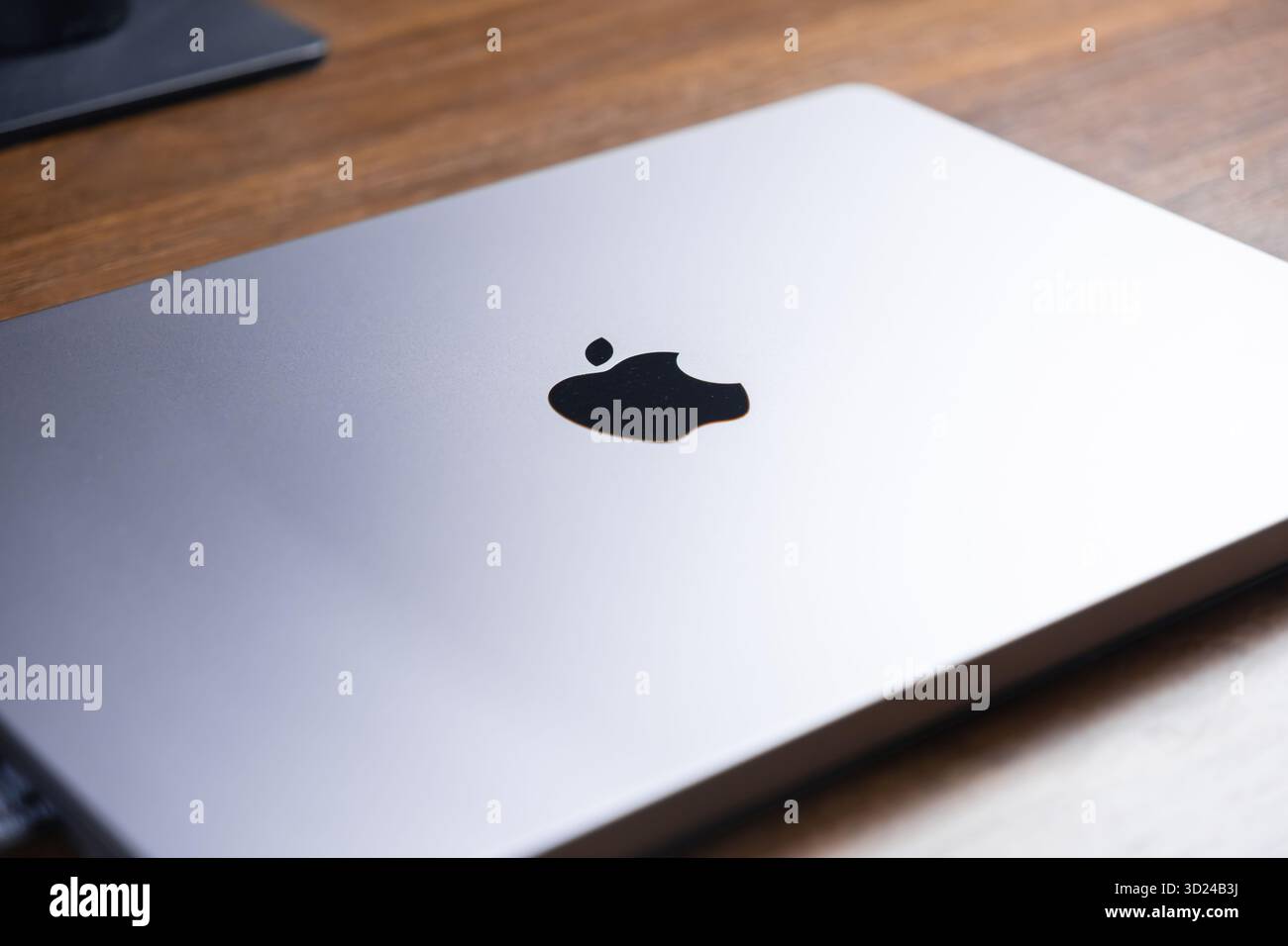 Poznan, Polonia - 18 settembre 2025: Primo piano dall'alto verso il basso di un computer portatile Apple in argento chiuso, con il suo iconico logo chiaramente visibile, appoggiato su un ricco legno Foto Stock