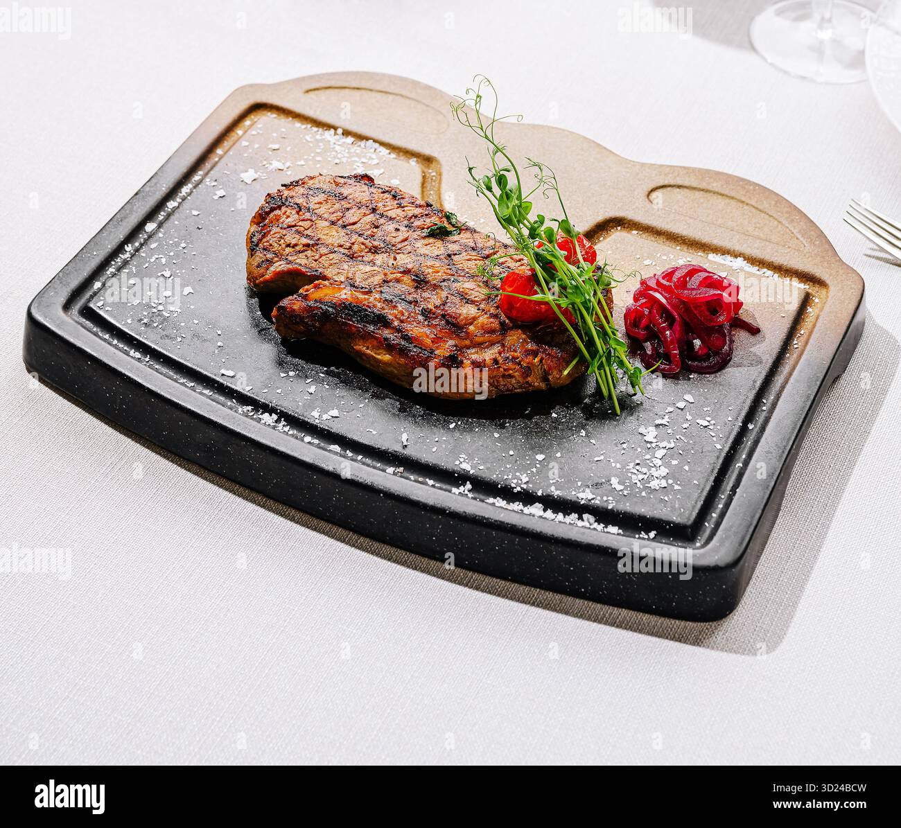 Bistecca alla griglia servita su un piatto di pietra sfrigolante con guarnigione Foto Stock