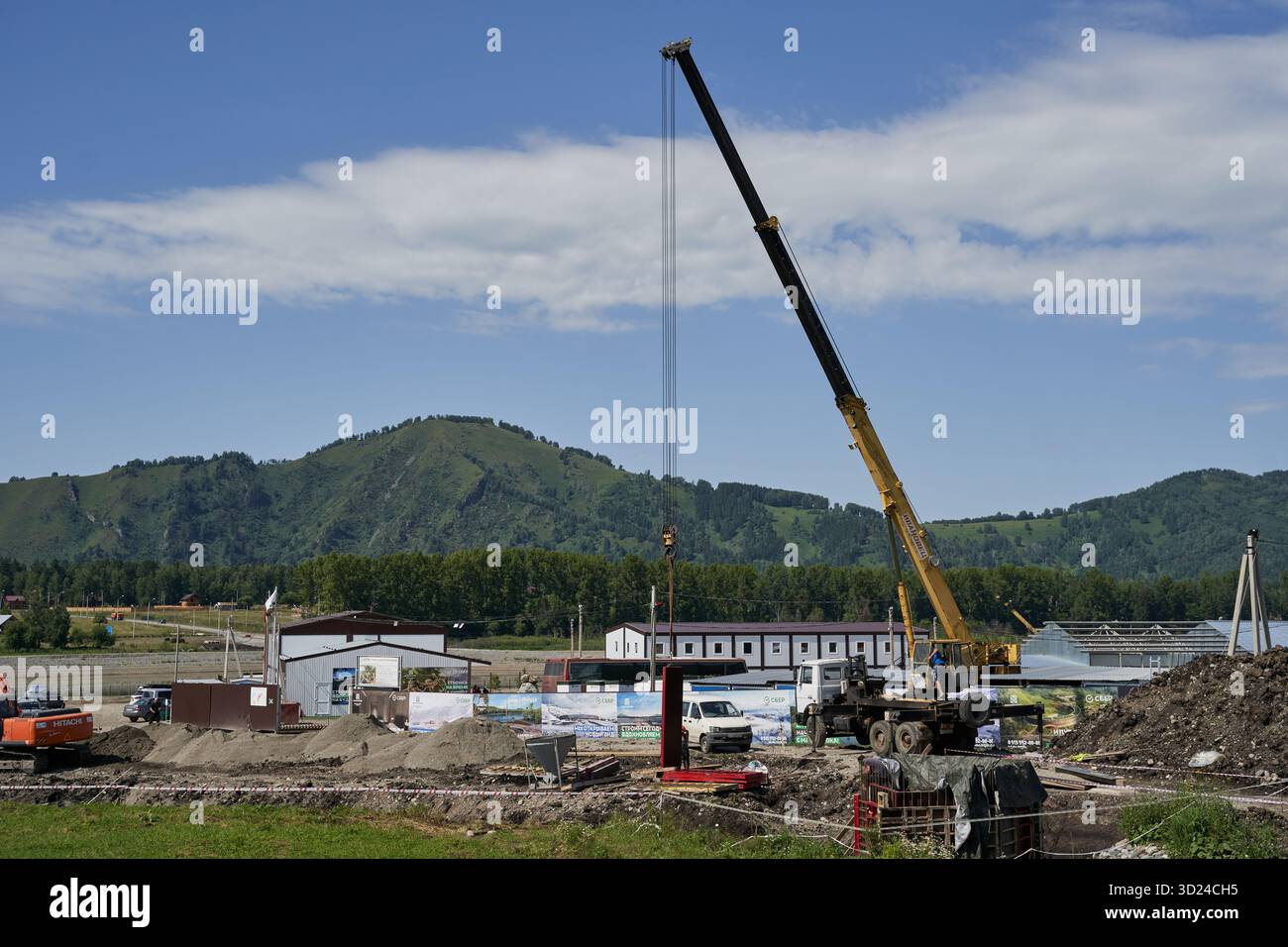 Cantiere con gru in un'area rurale montana sotto il cielo limpido Foto Stock