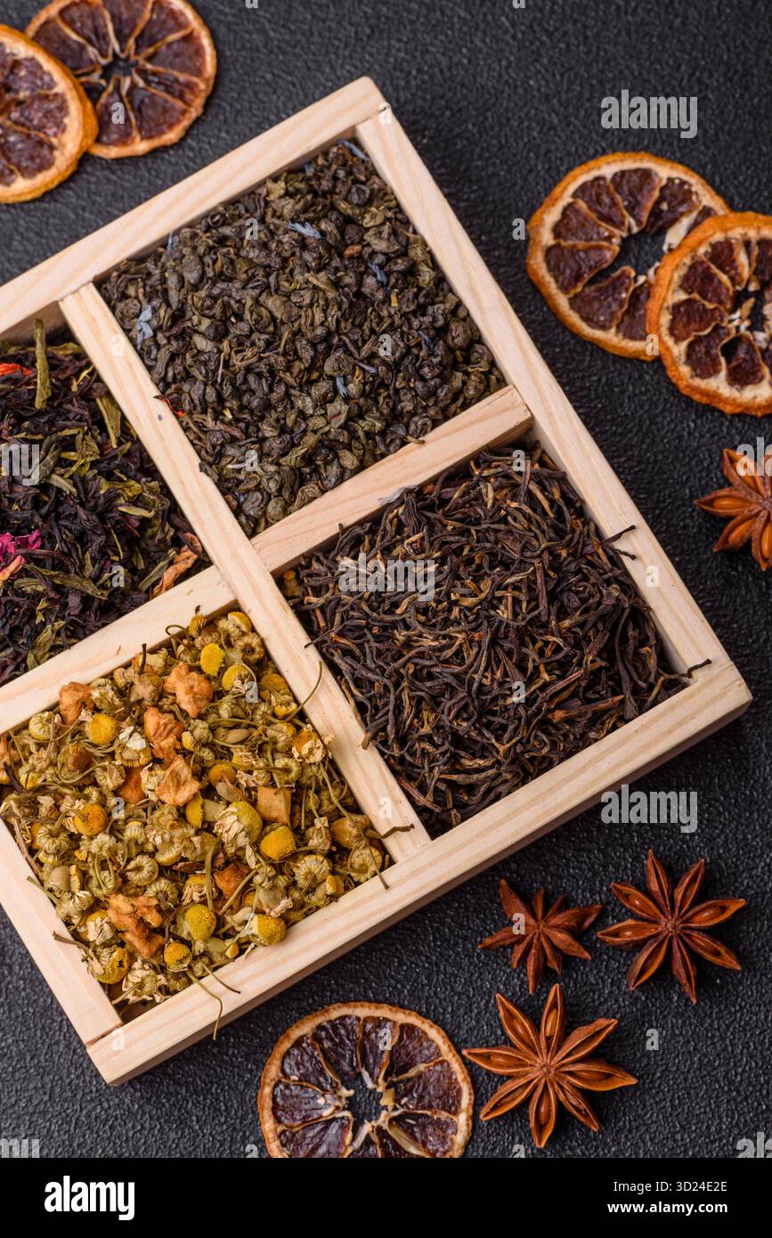Una scatola di legno con diversi tipi di tè secco, verde, nero, frutta e camomilla. Tè secco nella scatola Foto Stock