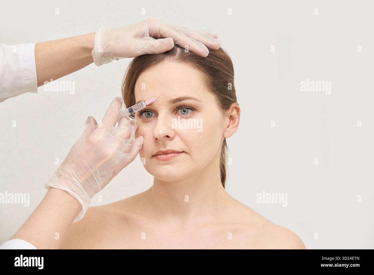 Donna caucasica che riceve un trattamento di iniezione cosmetica con guanti Foto Stock