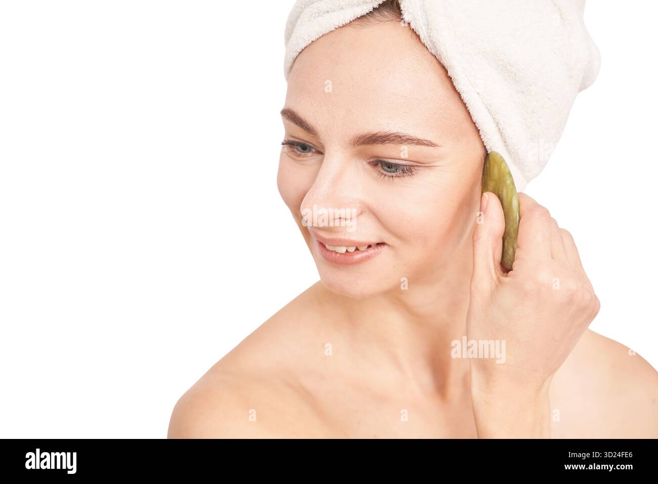 Donna caucasica adulta che utilizza giada naturale per il massaggio facciale nella cura della pelle Foto Stock