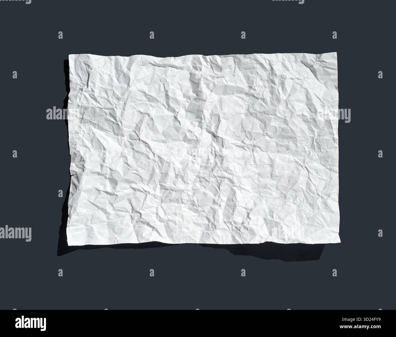 Carta bianca sgualcita su sfondo scuro che evidenzia texture e ombre Foto Stock