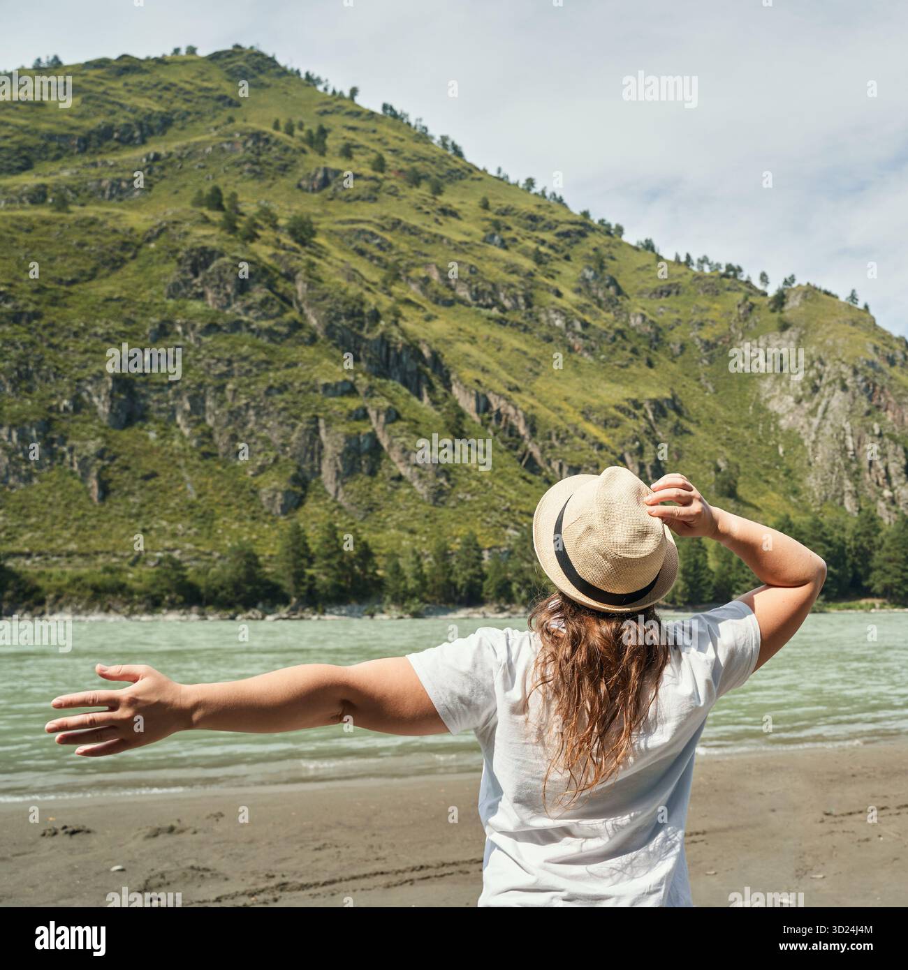 Donna che ama la natura in riva al fiume con vista sulle montagne, giovane asiatica Foto Stock