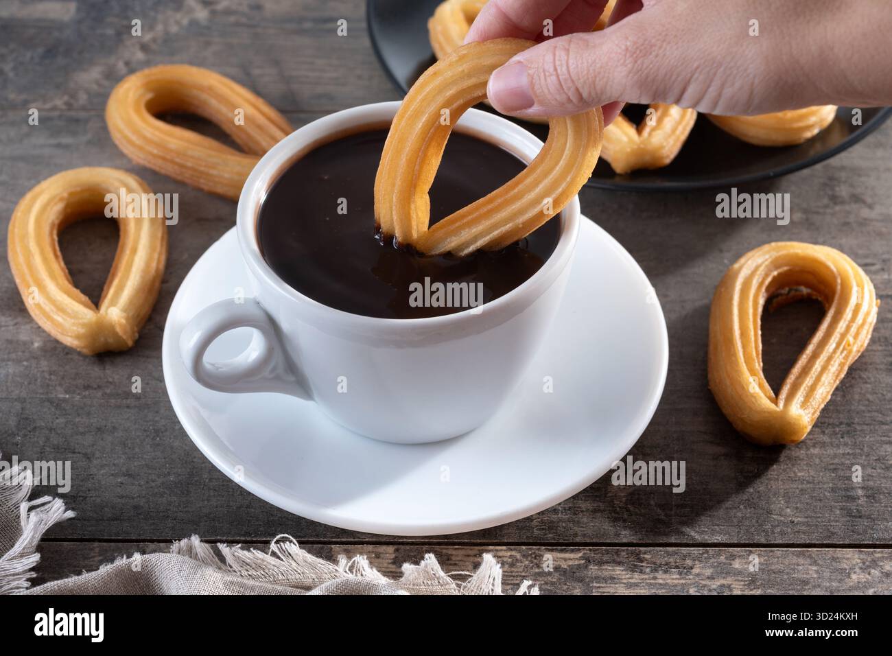 Churros spagnoli con cioccolata calda spessa in una tazza bianca su un tavolo di legno Foto Stock