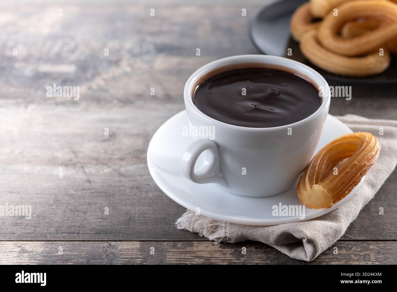 Churros spagnoli con cioccolata calda spessa in una tazza bianca su un tavolo di legno Foto Stock