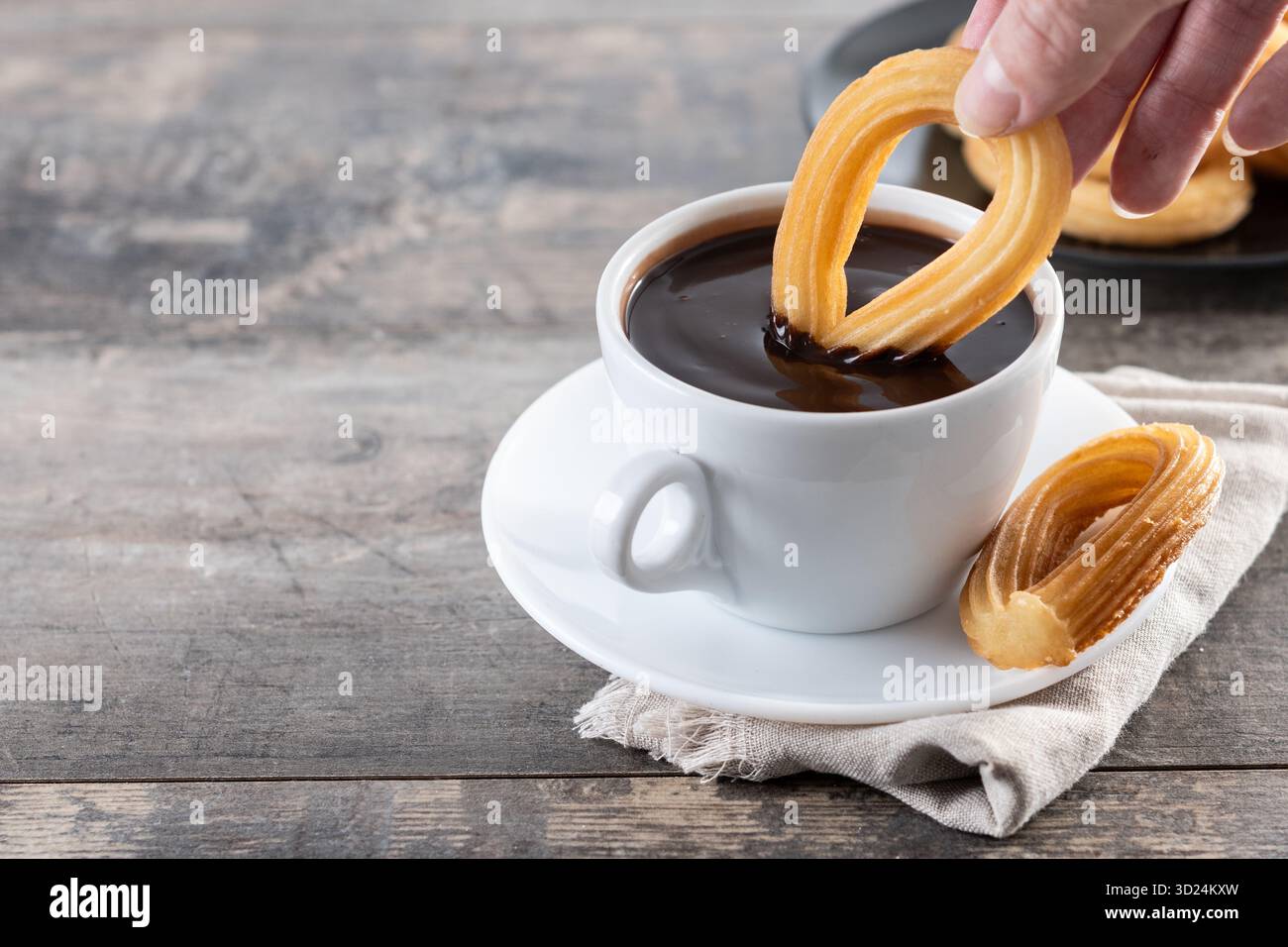 Churros spagnoli con cioccolata calda spessa in una tazza bianca su un tavolo di legno Foto Stock
