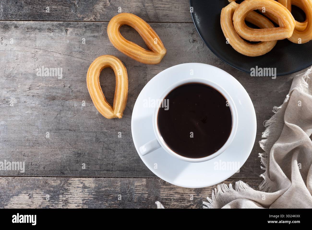 Churros spagnoli con cioccolata calda spessa in una tazza bianca su un tavolo di legno Foto Stock